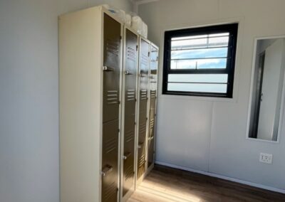 Interior of a converted shipping container with lockers and a window.