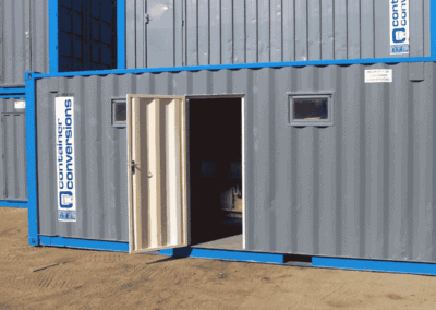 Container conversion with open door and small window on a construction site.